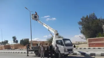 عمال صيانة يعملون على كشافات كهرباء في مدينة الحسنة